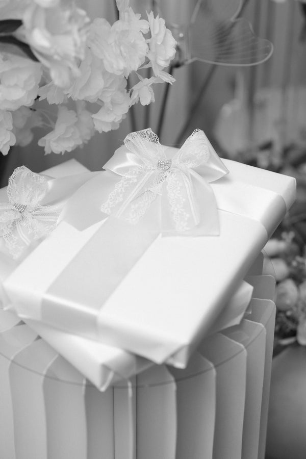 Elegant white gift boxes tied with satin ribbon and fresh flowers - how to present a Lunelle silk pillowcase as a beautiful luxury gift